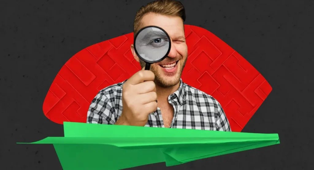 Homme souriant avec une loupe sur un fond rouge et noir, tenant un papier vert en forme d'avion.