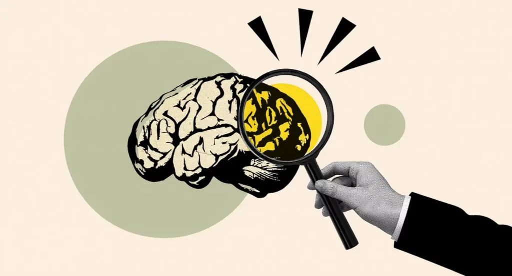 Main tenant une loupe sur un cerveau stylisé, symbolisant l'analyse et l'étude des pensées et comportements.
