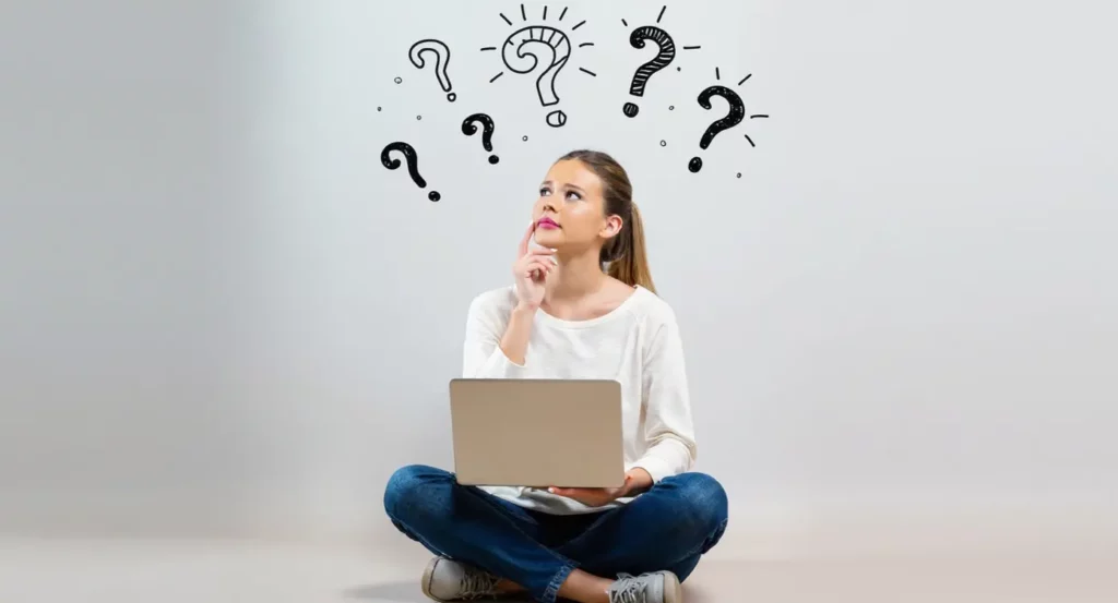 Femme pensant avec un ordinateur portable, entourée de symboles de question interrogatifs sur fond neutre.