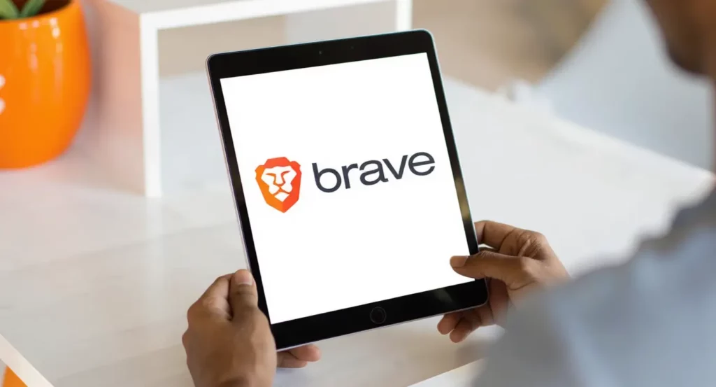 Logo de Brave affiché sur une tablette tenue par une personne, mettant en avant la navigation sécurisée.