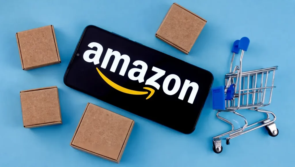 Smartphone affichant le logo d'Amazon, entouré de petits colis et d'un mini chariot de courses, sur fond bleu.