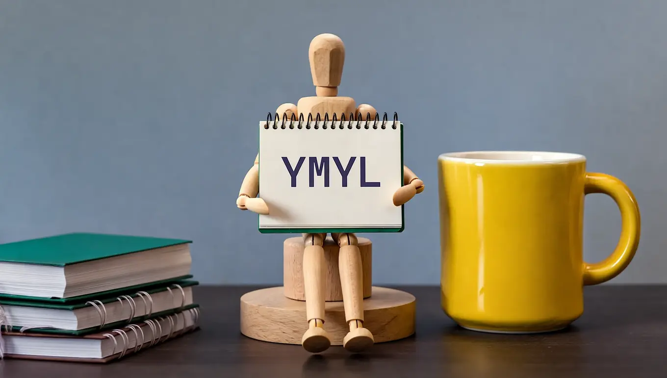 Poupée articulée tient un carnet avec le texte "YMYL" à côté d'une tasse jaune sur une table en bois.