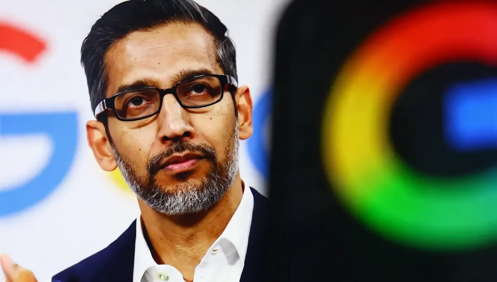 Homme d'affaires avec des lunettes et une barbe grise, devant un arrière-plan avec le logo Google coloré.