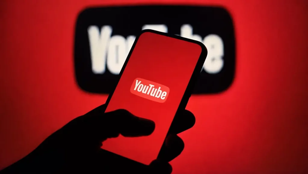Logo YouTube affiché sur un smartphone avec un arrière-plan rouge vibrant.