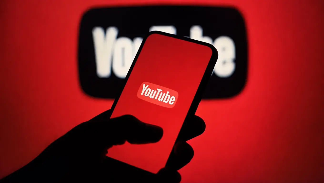 Logo YouTube affiché sur un smartphone avec un arrière-plan rouge vibrant.
